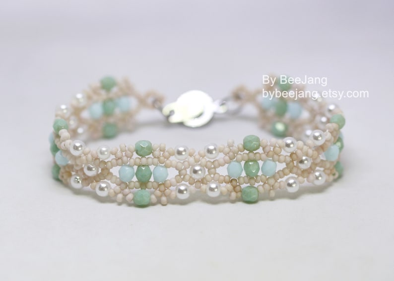 May include: A delicate bracelet with a silver clasp, featuring a multi-strand design of white, cream, and light green beads.