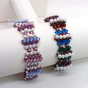 May include: Two beaded bracelets. One bracelet features purple, blue, and white beads. The other bracelet has red, blue, green, and white beads. The bracelets are displayed on a white surface. Text in the image reads "By Beeland bybee"