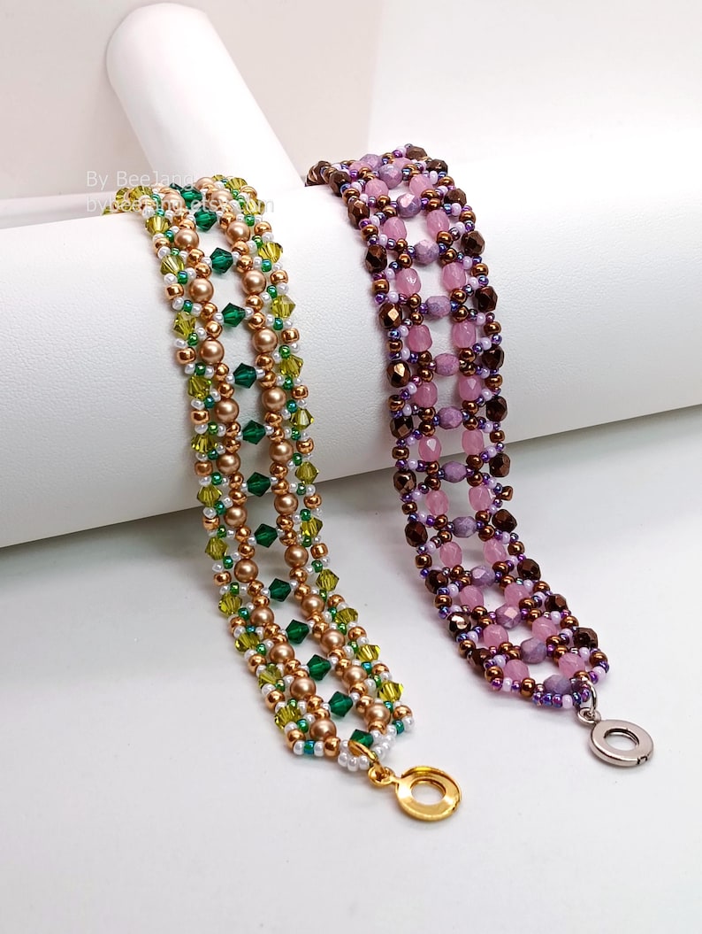 Two wide, handcrafted beaded cuff bracelets are shown with an intricate
Right Angle Weave lattice design. Each piece is meticulously woven with faceted bicone crystals, smooth round pearls, and delicate seed beads, secured with a metallic toggle clasp.
    Green Bracelet: Emerald and olive crystals with gold-toned pearls and a gold clasp.
    Purple Bracelet: Lavender and pink faceted beads with dark metallic bronze accents and a silver clasp.