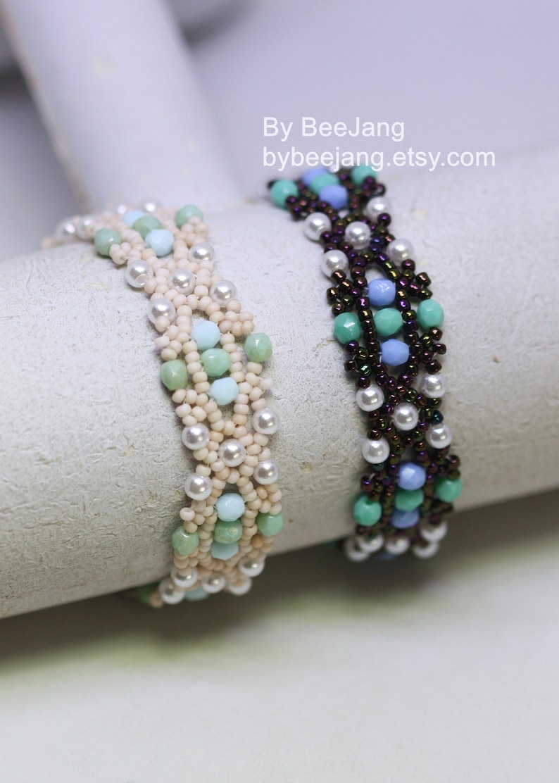 May include: Two beaded bracelets with a woven pattern. One bracelet is made with white, cream, and light blue beads. The other bracelet is made with dark brown, light blue, and green beads. The bracelets are displayed on a white surface. By BeeJang bybeejang.etsy.com