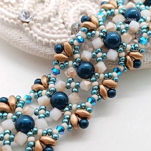 May include: A close-up of a beaded bracelet with navy blue, gold, and white beads. The bracelet has a multi-strand design with a mix of round and faceted beads. The beads are arranged in a repeating pattern, creating a textured and detailed look.