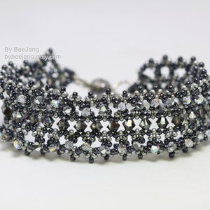May include: A beaded bracelet with a geometric pattern. The bracelet combines black, grey, and clear beads, creating a sparkling effect. The clasp is silver-toned. The text "By BeeJang" and a website address are visible.