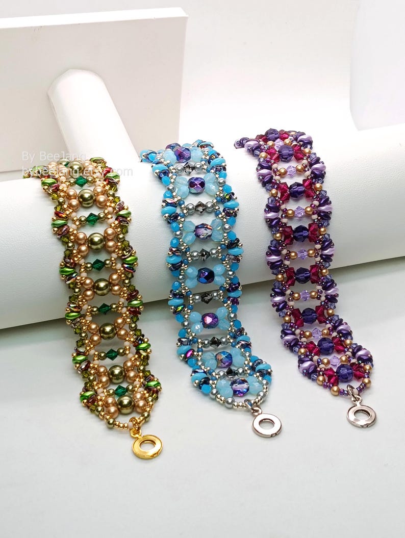 Puede incluir: Tres pulseras de cuentas en tonos verdes, dorados, azules, morados y rosas. Las pulseras est&aacute;n hechas con cuentas de varios tama&ntilde;os y formas, y tienen un cierre de metal. Las pulseras se exhiben sobre una superficie blanca.