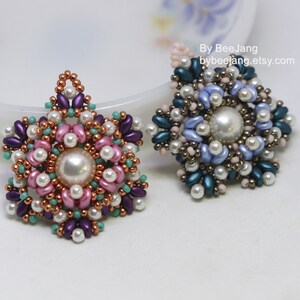 May include: Two beaded flower pendants with a pearl centre. One pendant is pink, purple, and teal, and the other is blue, teal, and brown.