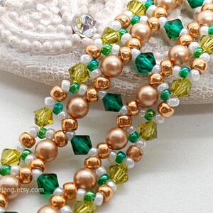 A close-up of a wide, handcrafted Right Angle Weave beaded bracelet. The intricate lattice design features emerald and olive green bicone crystals, metallic bronze round pearls, and small gold, white, and green seed beads. The beads are woven into an open, decorative pattern with a rich, textured finish.