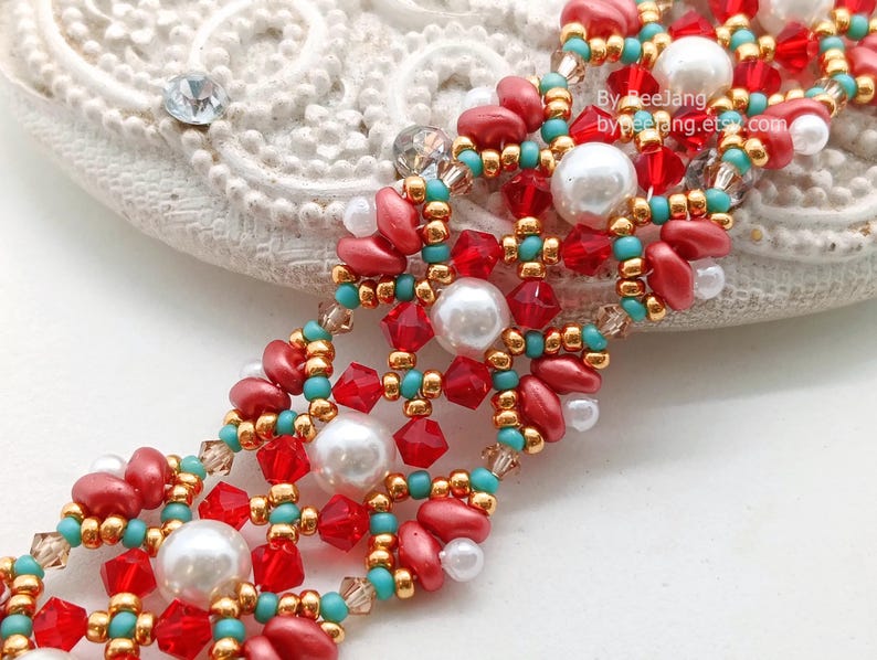 May include: A detailed beaded bracelet in red, white, gold, and turquoise. The intricate design incorporates various bead shapes and sizes. The text "By BeeJang, bypeejang.etsy.com" is visible on the image.
