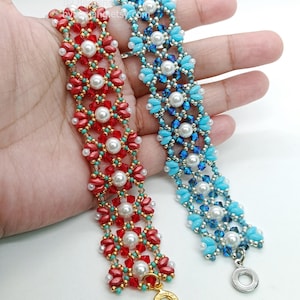 May include: Two beaded bracelets are shown, one red and the other blue. The red bracelet features red and turquoise beads with white pearls. The blue bracelet has blue and turquoise beads with white pearls. Both bracelets have a floral design.