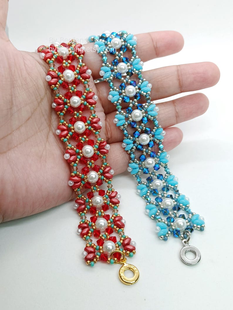 May include: Two beaded bracelets are shown, one red and the other blue. The red bracelet features red and turquoise beads with white pearls. The blue bracelet has blue and turquoise beads with white pearls. Both bracelets have a floral design.