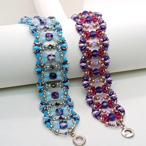 Puede incluir: Dos pulseras de cuentas. Una es azul claro con detalles plateados y azul oscuro. La otra es morada, rosa y dorada. Ambas tienen un patr&oacute;n repetitivo de cuentas y un cierre plateado.