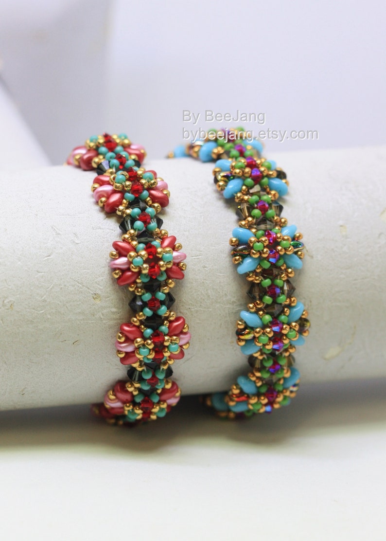 May include: Two beaded bracelets with floral designs. One bracelet features red, pink, and black beads with gold accents. The other bracelet has blue, green, and purple beads with gold accents. The bracelets are displayed on a white surface.