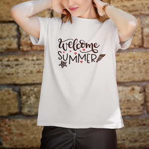 Könnte beinhalten: Weißes T-Shirt mit dem Schriftzug "Welcome Summer" in dekorativer Schrift. Das Design umfasst rote Herzen, einen Seestern und eine stilisierte Feder. Das Shirt ist aus weichem Material.