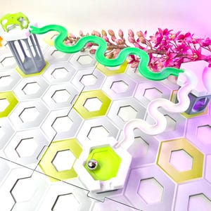 Puede incluir: Un colorido juego de canicas con una base de baldosas hexagonales. El juego presenta componentes blancos y verdes, incluyendo una pista verde en forma de serpiente y una pista blanca curva. El fondo incluye flores.