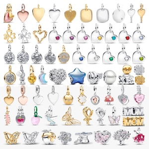 May include: A collection of various metal charms and pendants in gold and silver tones, featuring shapes like hearts, stars, butterflies, flowers, mushrooms, and letters. Some pieces include colorful enamel, embedded gemstones, or intricate textures.