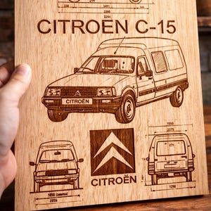 Puede incluir: Placa de madera con un diseño grabado de una furgoneta Citroën C-15, que incluye vistas laterales, frontal y trasera con medidas en milímetros. También aparece el logotipo de Citroën. Se muestra el texto "CITROEN C-15".