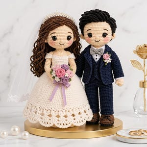 May include: A pair of crocheted dolls representing a bride and groom. The bride wears a white off-the-shoulder dress with a lace hem, a veil, and holds a bouquet of pink and purple flowers. The groom wears a navy blue suit with a gray bow tie.