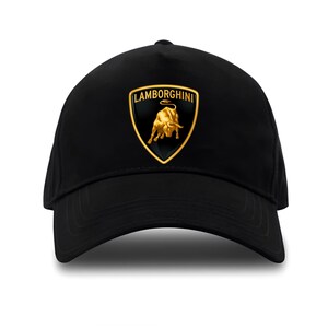 Può includere: Cappellino da baseball nero con il logo Lamborghini. Il logo è uno scudo dorato con un toro dorato e la scritta "Lamborghini" in oro. Il cappellino è realizzato in un tessuto scuro e liscio.