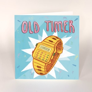May include: A blue and white card with the text "OLD TIMER" in pink letters. A yellow digital watch with a black display is in the centre of the card.