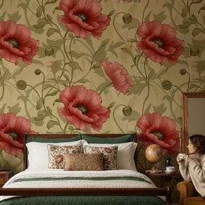 May include: A wooden bed frame with a dark green quilted coverlet and a white bed skirt. The bed is positioned against a wall featuring wallpaper with large red poppy flowers and green stems on a tan background. Two white pillows and three decorative throw pillows are arranged on the bed.