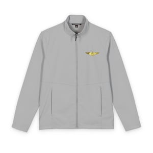 Peut inclure: Veste grise claire zippée avec un col montant. La veste présente un emblème doré sur le haut de la poitrine gauche et deux poches avant. La veste est de couleur unie et possède une fermeture éclair intégrale.