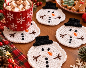 May include: A set of four round, white crocheted coasters shaped like snowmen, each featuring a black crocheted top hat, a small orange carrot nose, black button eyes, and brown stitched twig arms, arranged on a wooden surface.