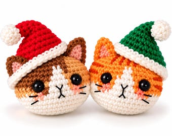 May include: Two round crochet cat heads with black plastic eyes and embroidered faces. One cat is brown and white wearing a red Santa hat, and the other is orange and white wearing a green Santa hat, both with white pom-poms.