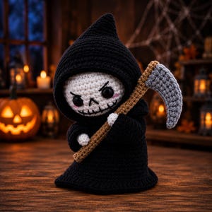 May include: A crocheted grim reaper doll featuring a black hooded cloak, a white skull face with black eyes, stitched eyebrows, and pink cheeks. The doll holds a scythe with a brown handle and a textured grey blade, crafted with yarn.