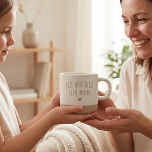 Op de afbeelding: Een witte keramische mok met een zwart handvat en de tekst "But First, Coffee" in een vetgedrukte, zwarte letter. De mok staat tegen een vage achtergrond. De mok is ongeveer 10 cm hoog.
