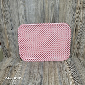 May include: A rectangular serving tray with a red and white checkered pattern. The tray has rounded corners and a glossy finish. The background is a wooden surface.