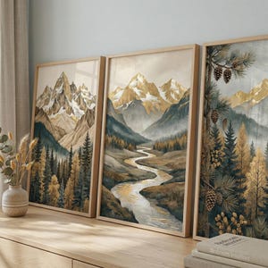 Könnte beinhalten: Drei gerahmte Landschaftskunst-Drucke mit Berglandschaften. Das Kunstwerk zeigt einen Fluss, der sich durch ein Tal schlängelt, mit goldfarbenen Bergen und immergrünen Bäumen. Die Rahmen sind aus hellem Holz und verleihen der Dekoration eine natürliche Note.