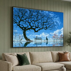 May include: A rectangular wall art print featuring a large, dark, leafless tree silhouetted against a bright blue sky with white clouds. A bench sits beneath the tree, with a small figure nearby, all reflected in a calm, mirror-like water surface.