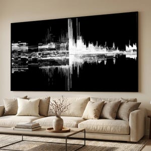 Op de afbeelding: Groot zwart-wit abstract kunstwerk. Het kunstwerk heeft een symmetrisch ontwerp met verticale en horizontale lijnen, die op geluidsgolven lijken. Het hangt boven een beige bank met kussens.