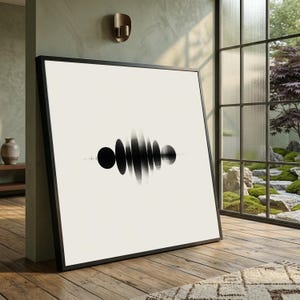 May include: Black and white abstract art print in a black frame. The artwork features a series of black oval shapes and lines, creating a visual representation of sound waves. The print is displayed on a light-colored wall.