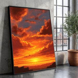 May include: Framed art print showing a dramatic sunset. The artwork displays a sky ablaze with orange, red, and yellow hues, with a bright sun near the horizon. The print is in a black frame, leaning against a concrete wall.