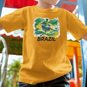 A child wearing a yellow t-shirt with a graphic of a soccer player and the word "BRAZIL" printed on it.