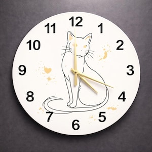 May include: White round wall clock featuring a black outline of a cat. The clock face has black numbers and gold-colored hands. Gold-colored paint splatters are around the cat illustration. A decorative item for a home or office.