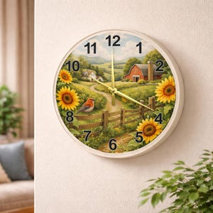 May include: A round wall clock with a cream-colored frame. The clock face features a pastoral scene with a red barn, sunflowers, and a bird. The clock hands are gold-colored. The clock measures approximately 12 inches in diameter.