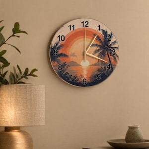 May include: Round wall clock featuring a sunset scene with palm trees and a vibrant orange and yellow sky. The clock face displays black numerals and gold hands. The clock is mounted on a beige wall.