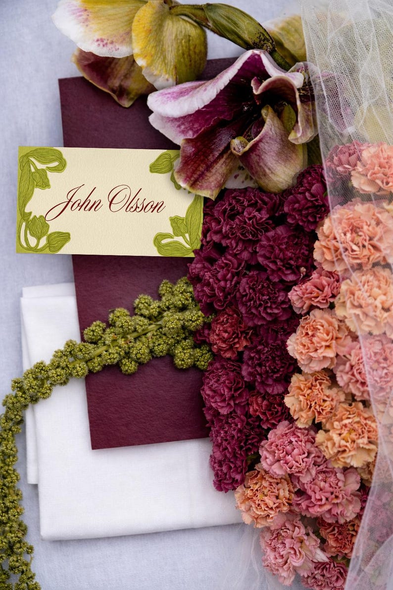 May include: A floral arrangement featuring orchids, carnations, and greenery. A cream-colored name card with the name "John Olsson" is visible. The flowers are in shades of burgundy, peach, and cream.