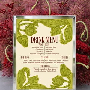 May include: A framed drink menu with a cream-colored background and green floral accents. The menu lists wine, beer, and cocktails, including "The Hers," "The His," and "The Theirs" selections. The background features red and pink foliage.