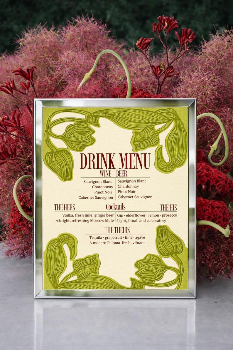 May include: A framed drink menu with a cream-colored background and green floral accents. The menu lists wine, beer, and cocktails, including "The Hers," "The His," and "The Theirs" selections. The background features red and pink foliage.