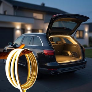 May include: A coiled, flexible LED light strip with a warm white glow is held in front of a black estate car with its boot open. The boot interior is illuminated by a similar light strip. A house is in the background.