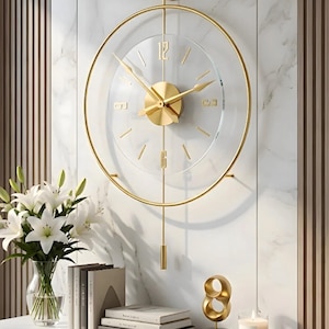 Pode incluir: Um relógio de parede circular com moldura de metal dourado e mostrador transparente. O relógio tem ponteiros dourados, marcadores de hora dourados e os números 12, 3, 6 e 9 em ouro. Um pêndulo dourado pende do centro e um suporte dourado.