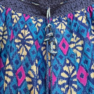 Puede incluir: Falda estampada con cinturilla de ganchillo y cord&oacute;n. La falda presenta un dise&ntilde;o vibrante de formas de diamante azules, amarillas y rosas. El cord&oacute;n es azul con un nudo decorativo.