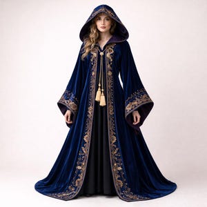 May include: A long, hooded velvet robe in a deep blue hue, adorned with intricate gold embroidery along the edges and sleeves. The robe features a flowing design with a matching hood and decorative tassels.