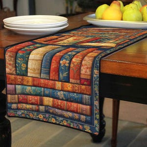 Peut inclure: Chemin de table rectangulaire avec un motif de livres empilés. Le chemin de table a une bordure bleu foncé avec des motifs floraux et un motif central de livres de différentes couleurs, dont le rouge, le bleu et l'or. Il est posé sur une table en bois.