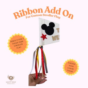 May include: A white stroller flag with a black Mickey Mouse head and a red star. The flag has the text "T WE" and is adorned with colorful ribbons. The image also includes text that says "Ribbon Add On" and "Choose Your Color Theme".