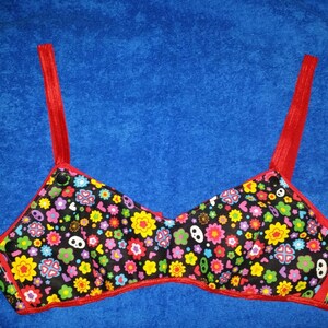 May include: A black bra with red straps and a floral print featuring colorful flowers, hearts, and skulls.