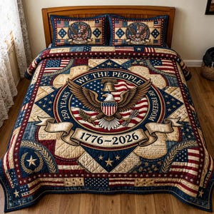Könnte beinhalten: Ein patriotisches Bettwäsche-Set mit einem zentralen Emblem mit Adler, Glocke und amerikanischer Flagge. Die Steppdecke und zwei Kissenbezüge zeigen den Text "We The People" und "1776-2026" in Rot, Weiß und Blau.