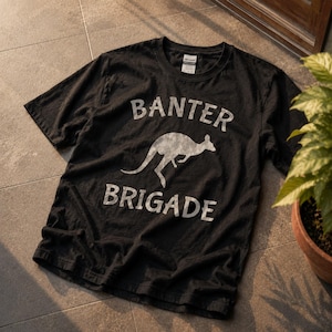 May include: A black short-sleeved t-shirt featuring a white graphic of a kangaroo in the center. The text BANTER is printed in a white arched font above the kangaroo, and the word BRIGADE is printed in a white font below the kangaroo.