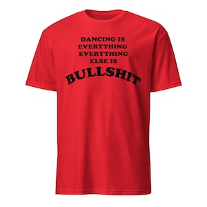 Könnte beinhalten: Ein leuchtend rotes Kurzarm-T-Shirt mit schwarzem Textaufdruck auf der Brust, der lautet: DANCING IS EVERYTHING EVERYTHING ELSE IS BULLSHIT. Das Kleidungsstück hat einen Rundhalsausschnitt und eine Standardpassform mit kräftiger Typografie.